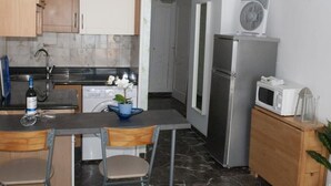 Een kleine keuken met houten kastjes, een roestvrijstalen koelkast, een magnetron en een spoelbak.
