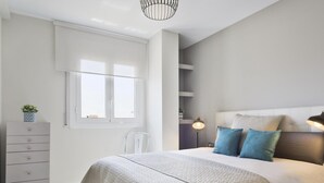 A bedroom with a bed, bedside tables, a dresser, a chair, a window, and a lamp.