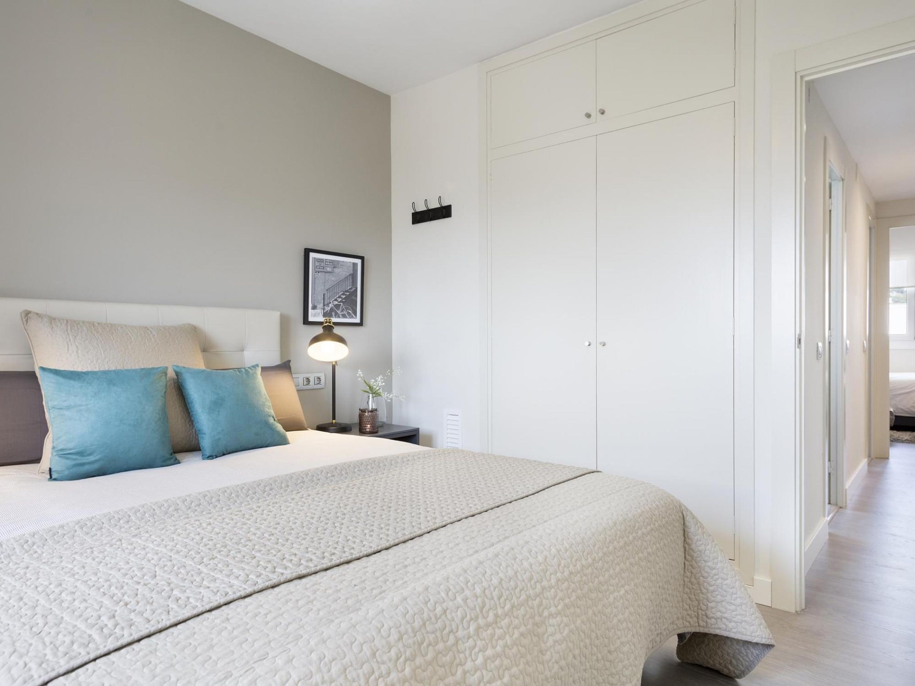 A bedroom with a bed, nightstands, a lamp, a picture on the wall, and a wardrobe.