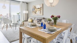 A modern dining area with a wooden table, white chairs, and a hanging light fixture.