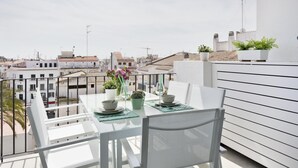 A balcony with a table set for two, overlooking a cityscape.