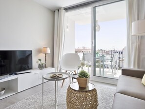 Een moderne woonkamer met een flatscreen-tv, een bank, een salontafel en een balkon met uitzicht op de stad.