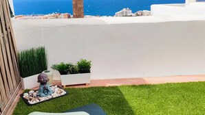 A small outdoor area with artificial grass, a cushion, a statue, and potted plants. - Tess Mirador de Ensue o con Vistas Panor Micas (Adeje)