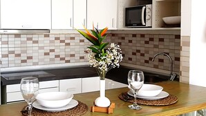 A modern kitchen with white cabinets, a microwave, and a tiled backsplash. - Tess Mirador de Ensue o con Vistas Panor Micas (Adeje)