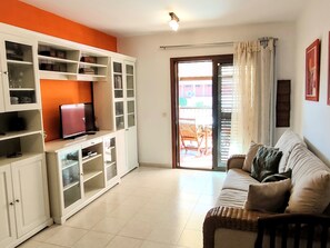 A living room with a sofa, TV, and built-in shelving unit. - CM 2 bd Cerca del mar (Granadilla de Abona)