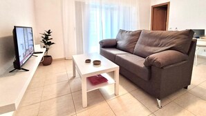 Ett vardagsrum med en soffa, ett soffbord, en tv och en växt.