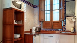 A compact kitchen with wooden cabinets, a built-in microwave, and a window with a view. - Apartamento Fajalauza (Granada)