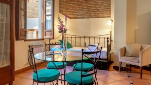 A cozy room with a bed, a round table with chairs, a chair, a lamp, and a window with curtains. - Apartamento Fajalauza (Granada)