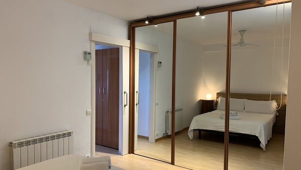 A bedroom with a bed, a bedside table, a mirror, a radiator, and a wardrobe. - Ground Floor in Sitges (Sitges)