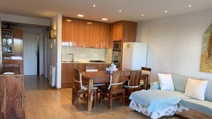 A modern apartment with a wooden dining table, a sofa, and a kitchen area. - Ground Floor in Sitges (Sitges)
