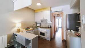 Una cocina compacta con armarios blancos, horno empotrado y un pequeño comedor.