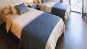 Habitación de hotel con dos camas, un ventanal grande y un balcón.