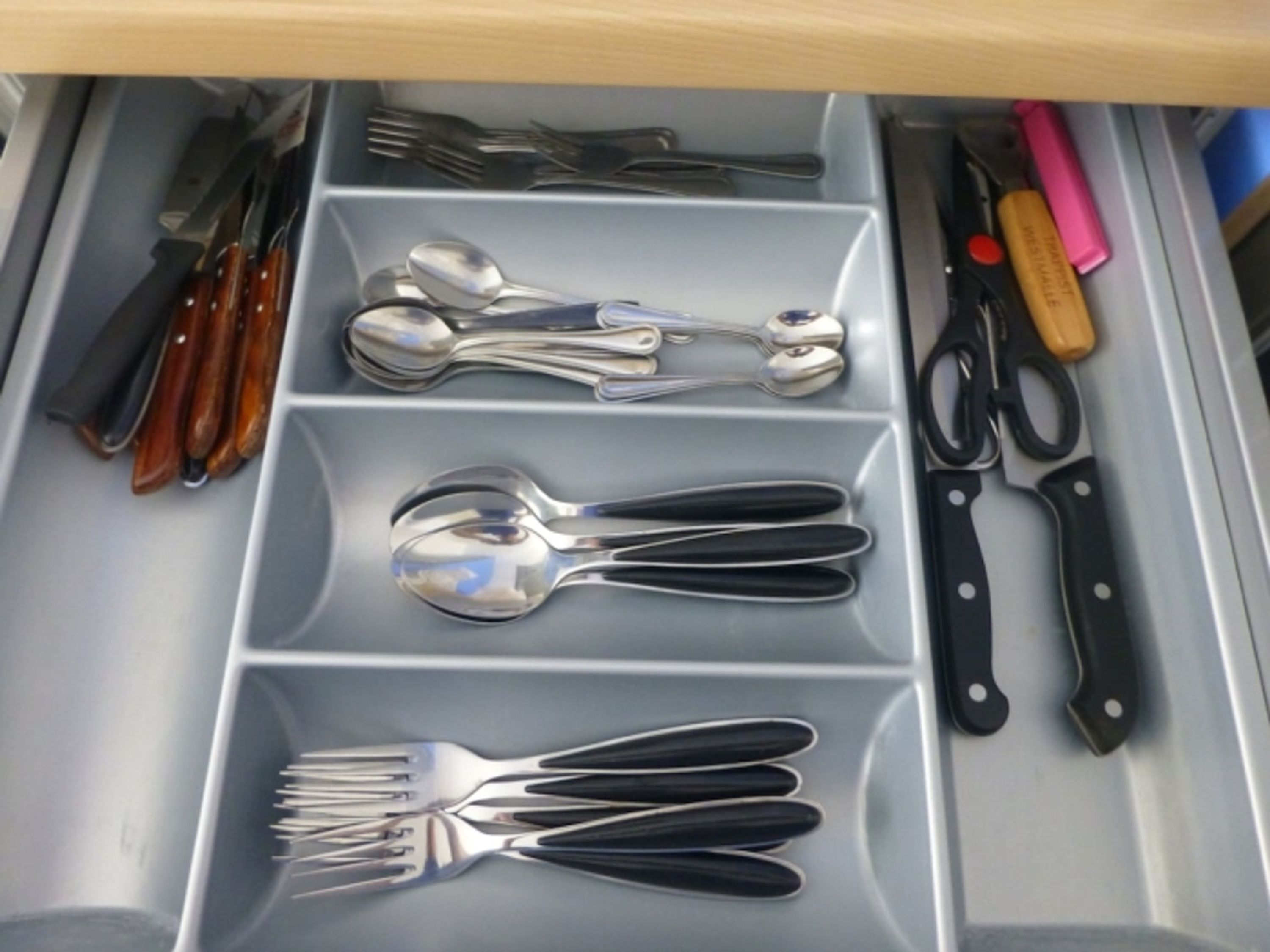 A drawer with utensils including forks, spoons, and knives.