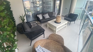 A balcony with a sofa, chairs, and a table.