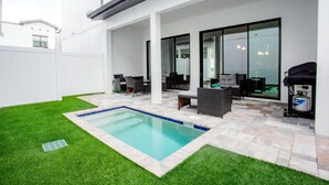 A modern outdoor patio with a swimming pool, outdoor furniture, and a grill area. - Townhome- 4Bd - Close To Parks Shops (Davenport)