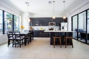 A modern kitchen with dark cabinets, a central island, and pendant lighting. - Townhome- 4Bd - Close To Parks Shops (Davenport)