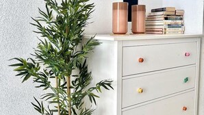 A white dresser with multiple drawers and a shelf above it holding books and two copper-colored vases. - C Ntrico y Acogedor Ideal Para Explorar la Ciudad (Alicante)