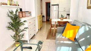 A compact living space with a sofa, a glass table, a dining table, and a kitchen area. - C Ntrico y Acogedor Ideal Para Explorar la Ciudad (Alicante)