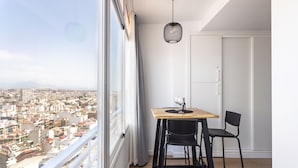 A balcony with a wooden table, two black chairs, and a hanging light fixture. - Luxury Views Downton (Alicante)