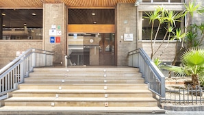 A building entrance with a staircase leading to a door, a brick wall, and a sign indicating a business center. - Luxury Views Downton (Alicante)