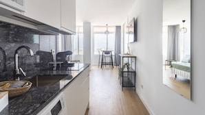 A modern kitchen with a marble countertop, a built-in oven, and a dining area with a table and chairs. - Luxury Views Downton (Alicante)
