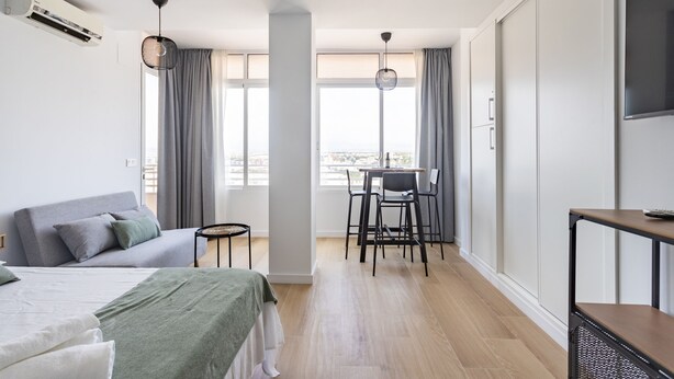 A modern hotel room with a bed, a desk, and a view of the city. - Luxury Views Downton (Alicante)