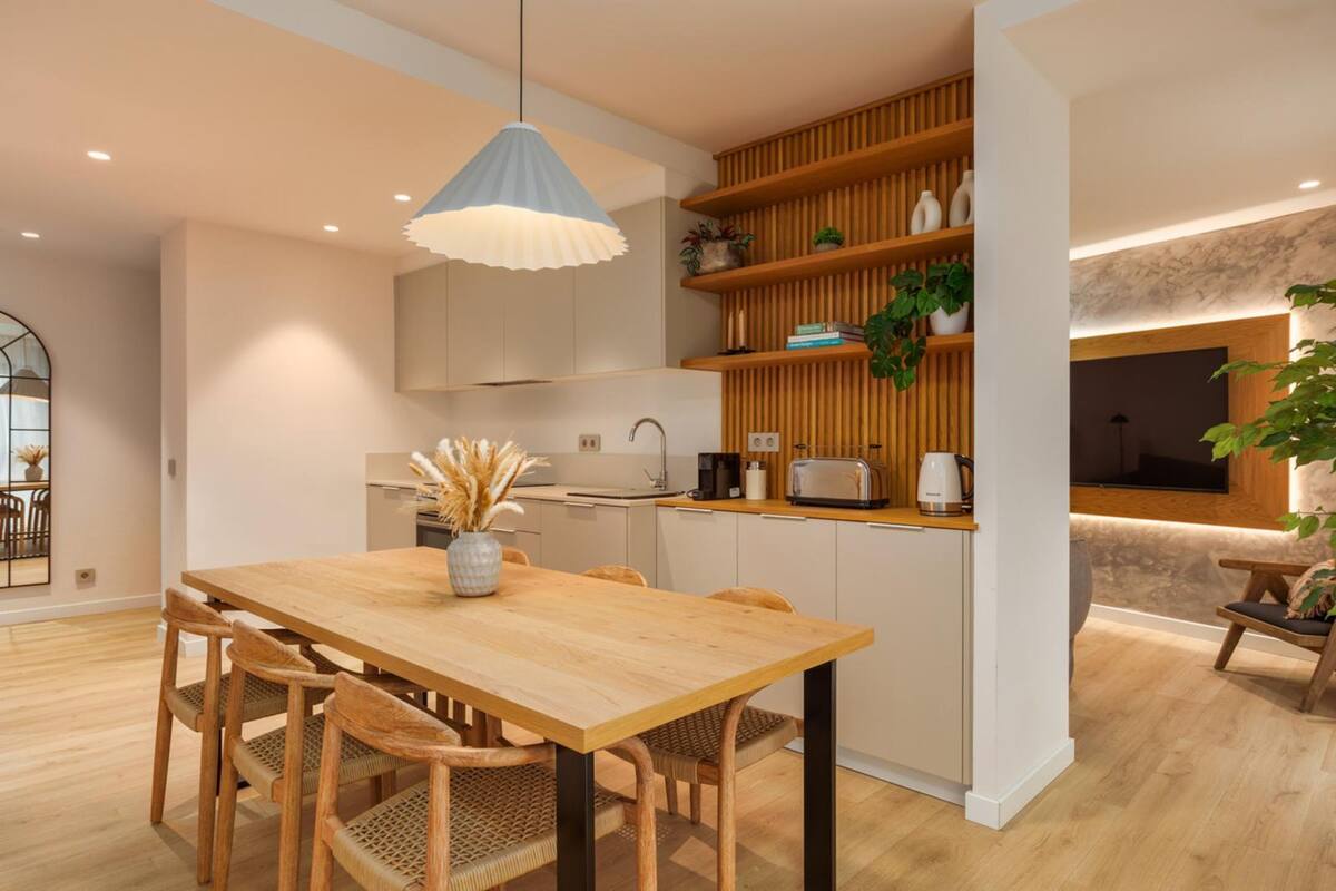 Eine moderne Küche mit Holzschränken, einer Mittelinsel und einer Pendelleuchte.