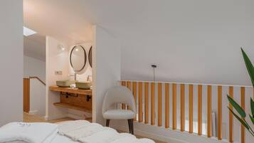 Une salle de bain moderne avec un puits de lumière, des éléments décoratifs en bois, une chaise blanche et un porte-serviettes blanc.