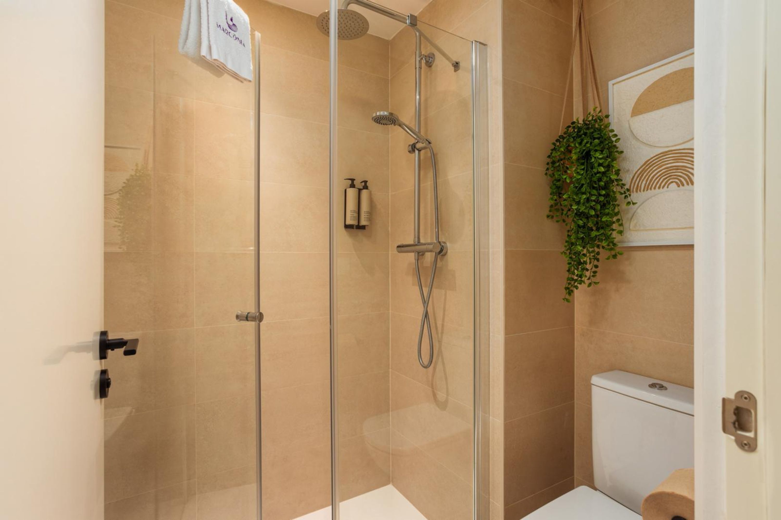 A modern bathroom with a glass-enclosed shower, a toilet, and a sink.