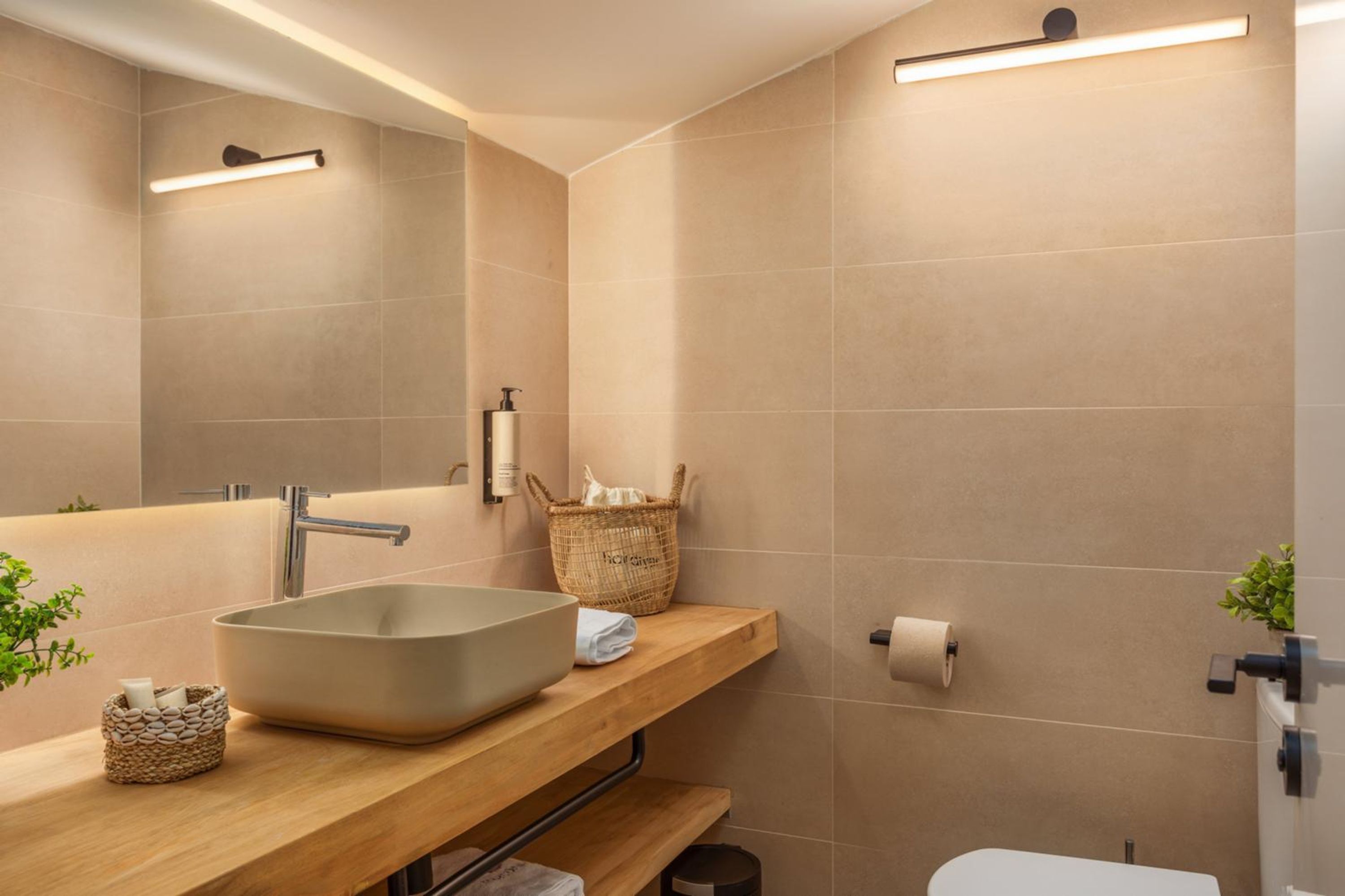 Une salle de bain moderne avec un grand lavabo sur pied, un meuble-lavabo en bois, un miroir et des toilettes.