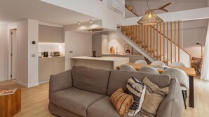 A modern interior with a sofa, dining table, kitchen, and staircase.