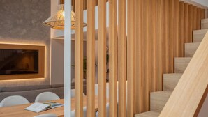 A modern interior with a wooden staircase, a fireplace, and a dining area with chairs and a table.