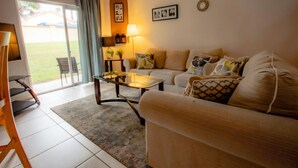A living room with a sofa, coffee table, and a glass door leading to a patio. - Where Memories Flourish 8 Mins to Disney (Davenport)