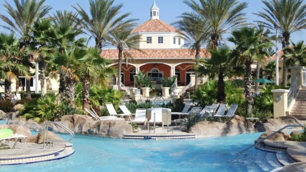 A resort with a large pool, palm trees, and a building with a red roof. - Where Memories Flourish 8 Mins to Disney (Davenport)