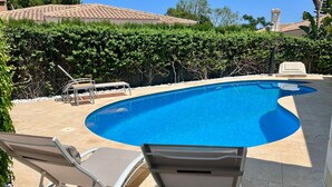 Piscina com espreguiçadeiras e um telhado telhado ao fundo.