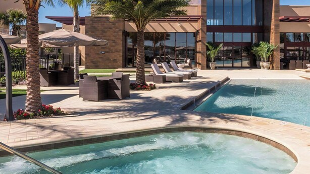 A pool area with lounge chairs and a hot tub.