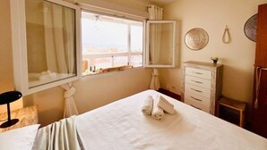Una habitación de hotel con cama, ventana con cortinas, cómoda y ventilador de techo.