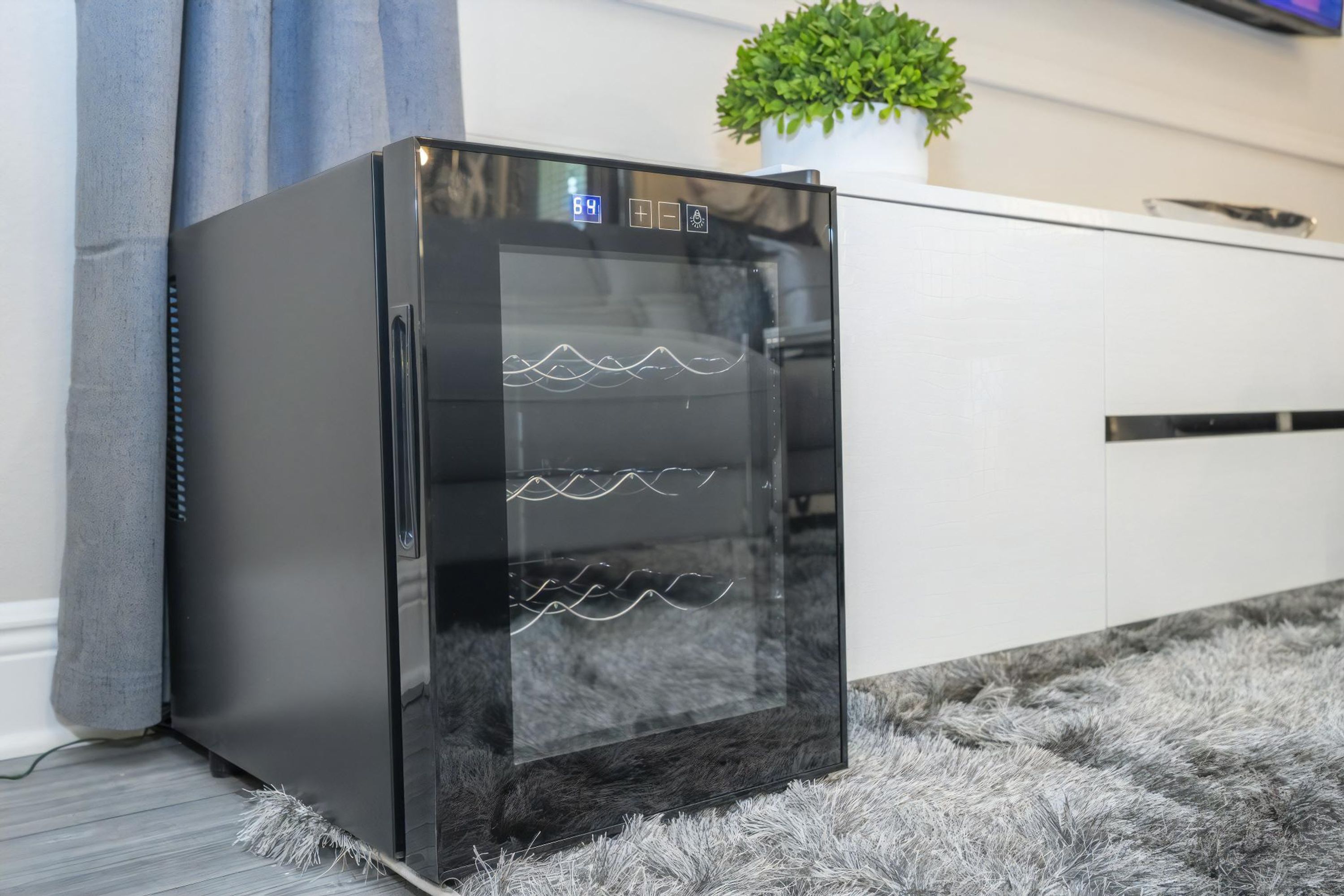 Un réfrigérateur noir doté d’un écran numérique, un meuble blanc et un tapis moelleux.