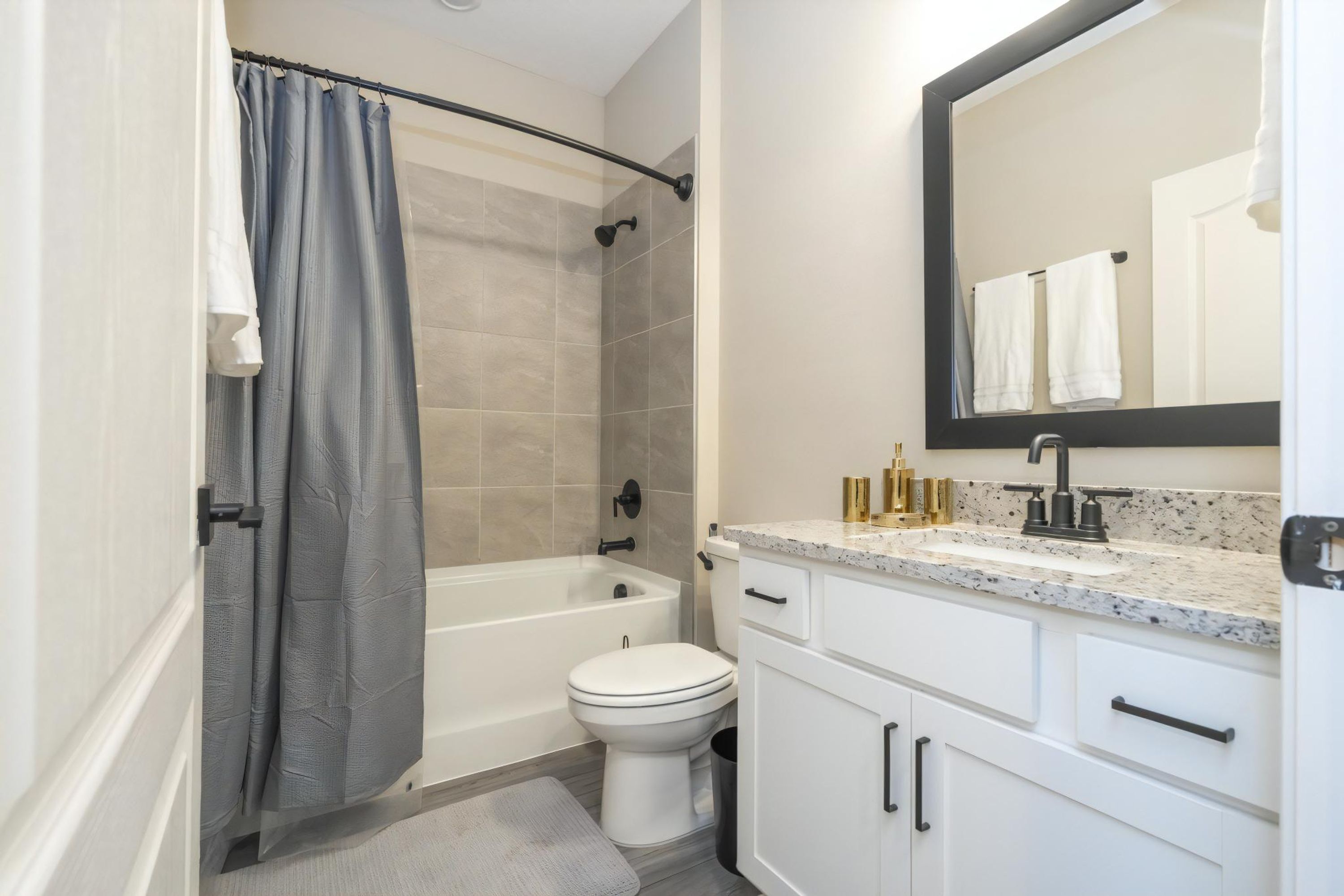 A modern bathroom with a bathtub, toilet, and vanity.