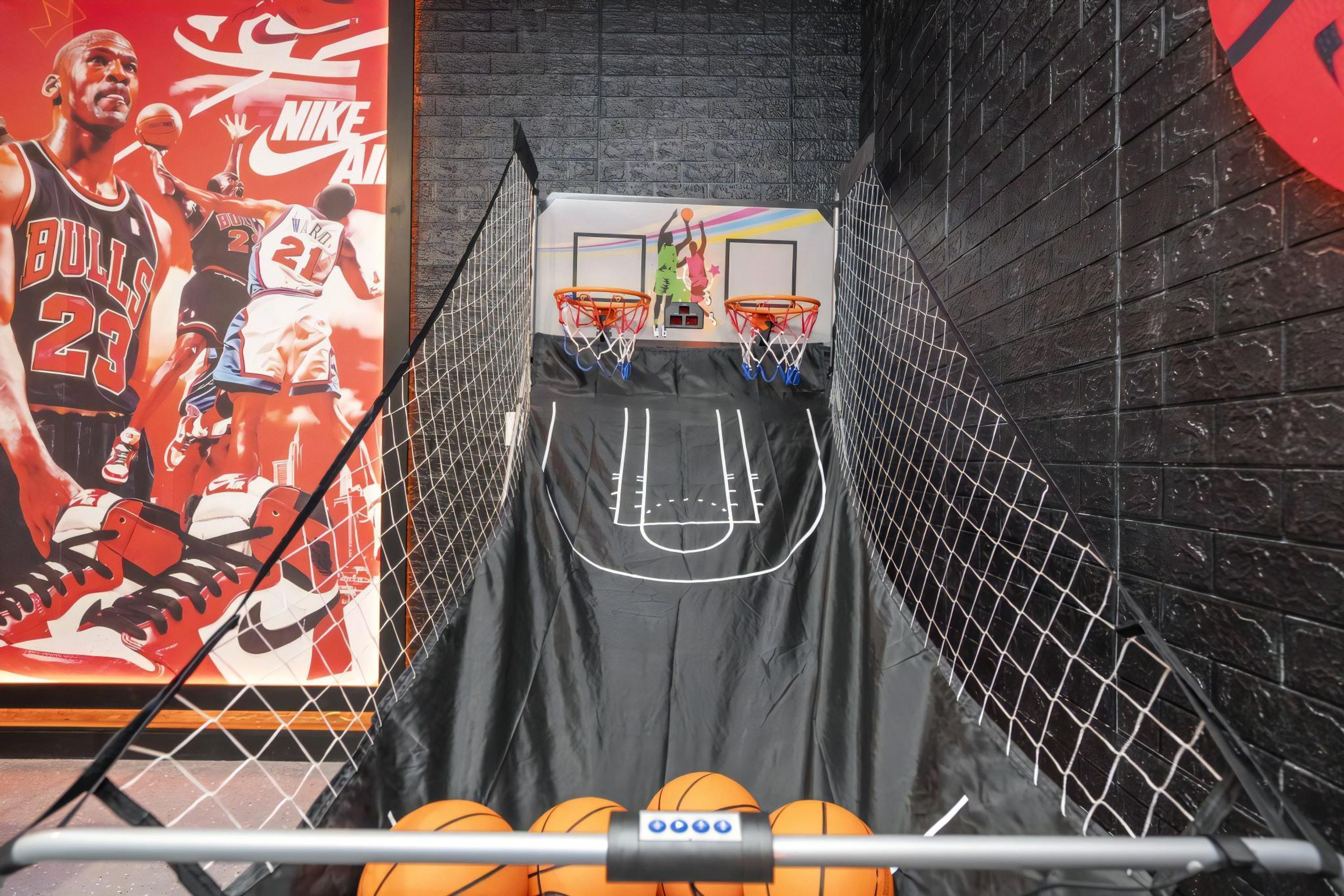 A basketball hoop with a net, two basketballs, and a basketball court outline on a wall.
