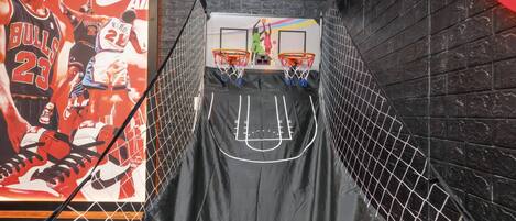 A basketball hoop with a net, two basketballs, and a basketball court outline on a wall.