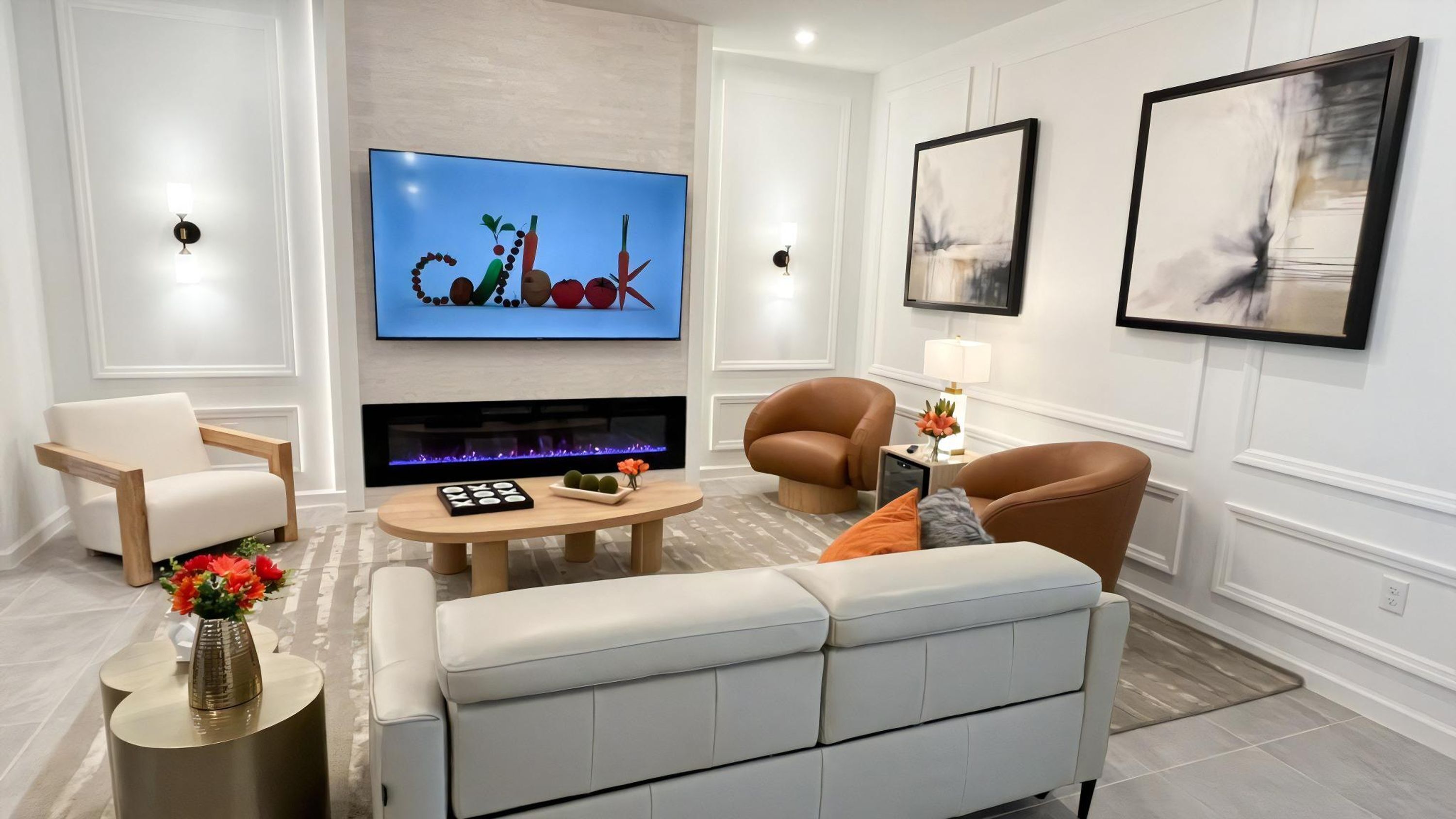 A modern living room with a flat-screen TV, a fireplace, comfortable seating, and artwork on the walls.