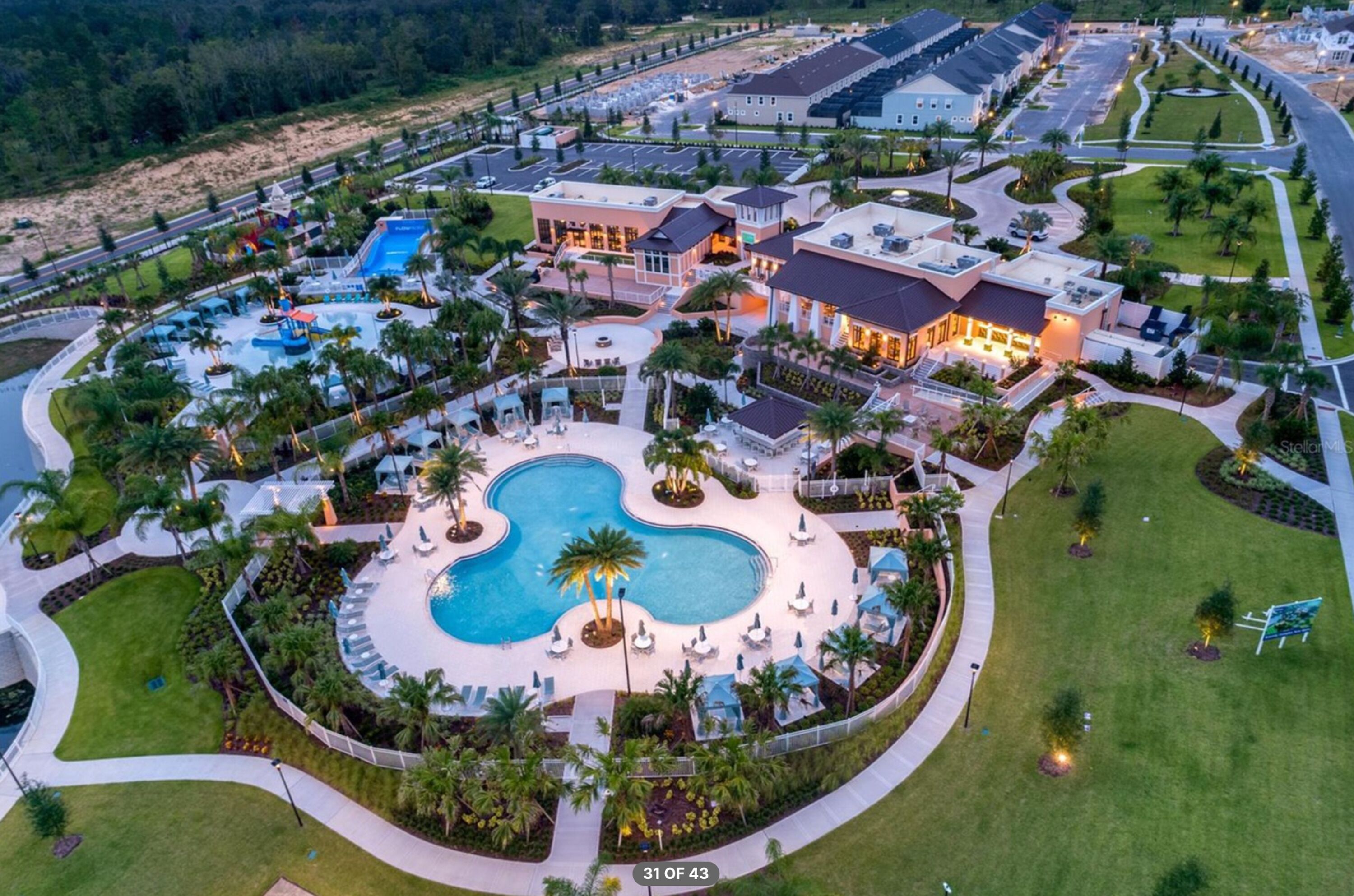 Un resort con una amplia piscina central, varias edificaciones y zonas ajardinadas.