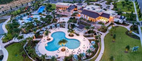 Un resort con una amplia piscina central, varias edificaciones y zonas ajardinadas.