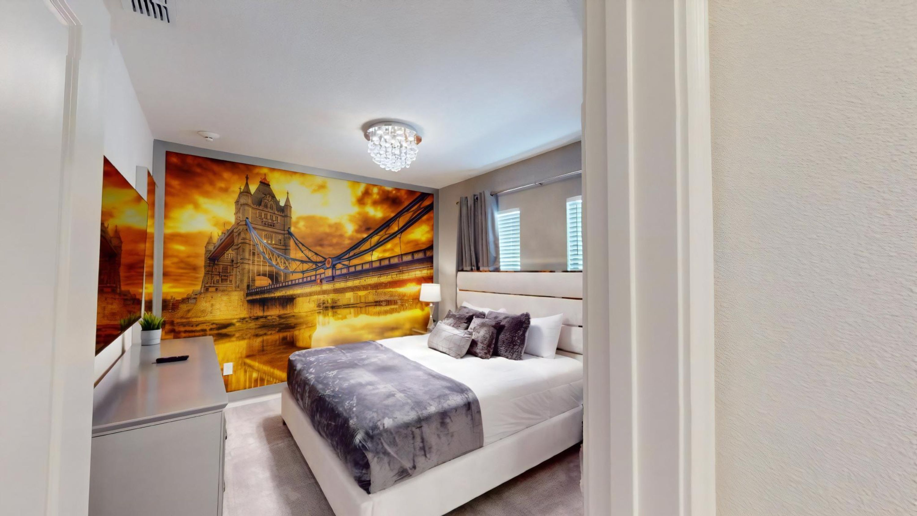A modern bedroom with a large bed, a nightstand, a wall-mounted lamp, and a ceiling light fixture.