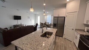 A modern kitchen with granite countertops, stainless steel appliances, and white cabinetry.