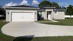 A two-story house with a garage, a covered porch, and a well-maintained lawn.