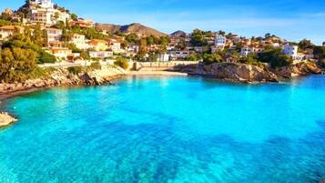 Un pueblo costero con edificios en una colina que dominan un mar azul y transparente.