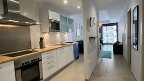 Een moderne keuken met roestvrijstalen apparatuur, witte keukenkastjes en uitzicht op de woonkamer.
