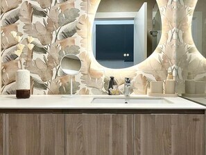 Un baño con un espejo grande, un lavabo y un tocador con un armario de madera.